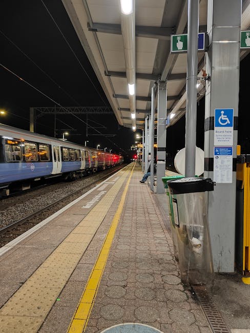 Finsbury Park railway station platform viewed from the outside, showing a covered waiting area with several metal benches arranged along the platform. The platform has tactile paving strips near the e