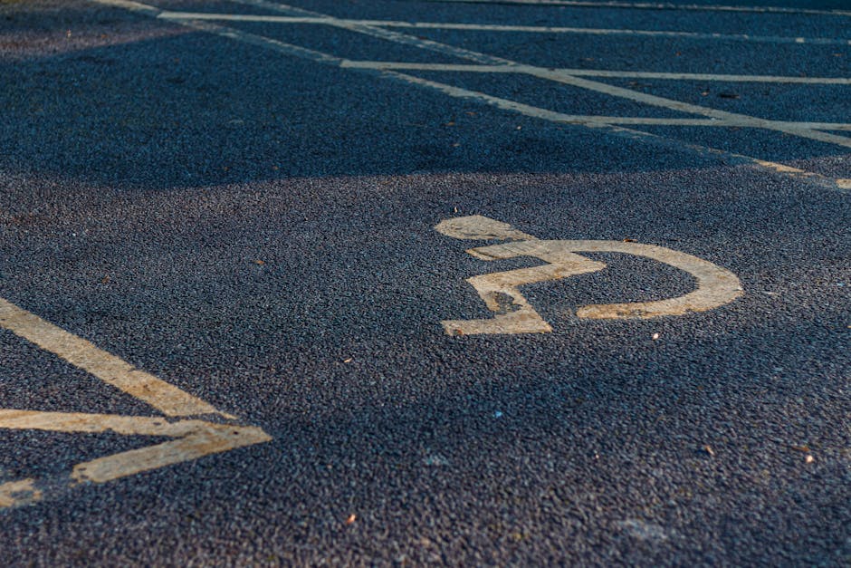 Close-up view of a designated parking space with the number '22' painted in white on dark asphalt. The parking spot is outdoors, with the painted lines of adjacent spaces visible nearby. The surface shows small embedded pebbles and slight signs of wear, typical of a public or residential parking lot. This image captures the process of planning or preparing for a home relocation, as part of furniture transport or moving logistics, with the parking area's layout aiding in vehicle access. The context relates to house removals services provided by Man With a Van Barnsbury, emphasizing the importance of parking and access considerations during a move in the Barnsbury area, aligned with the 'Islington Green Moves' guide on parking and access tips.